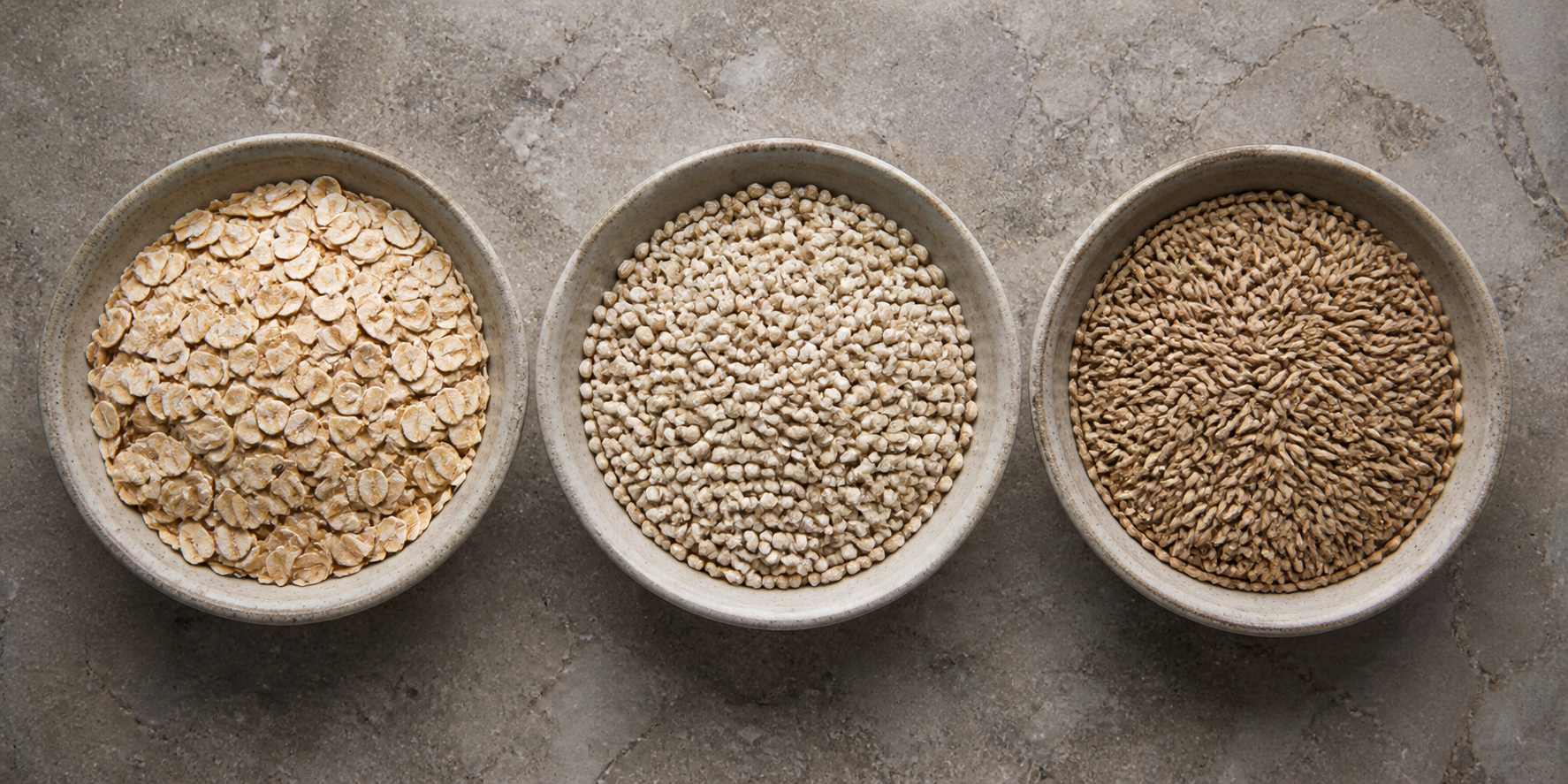 Three equal bowls of oats, barley and rye arranged for a neutral GI-comparison guide.